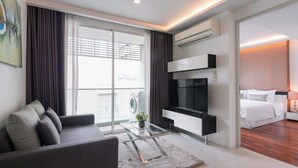 A modern living room with a sofa, TV, and a glass coffee table. - Beverly33 (Bangkok)