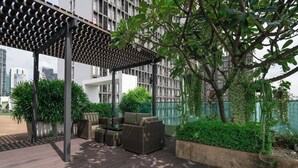 An outdoor patio with a pergola, seating area, and lush greenery. - Beverly33 (Bangkok)