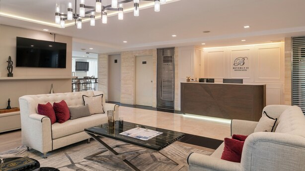 A modern hotel lobby with a reception desk, seating area, and a large flat-screen TV. - Beverly33 (Bangkok)