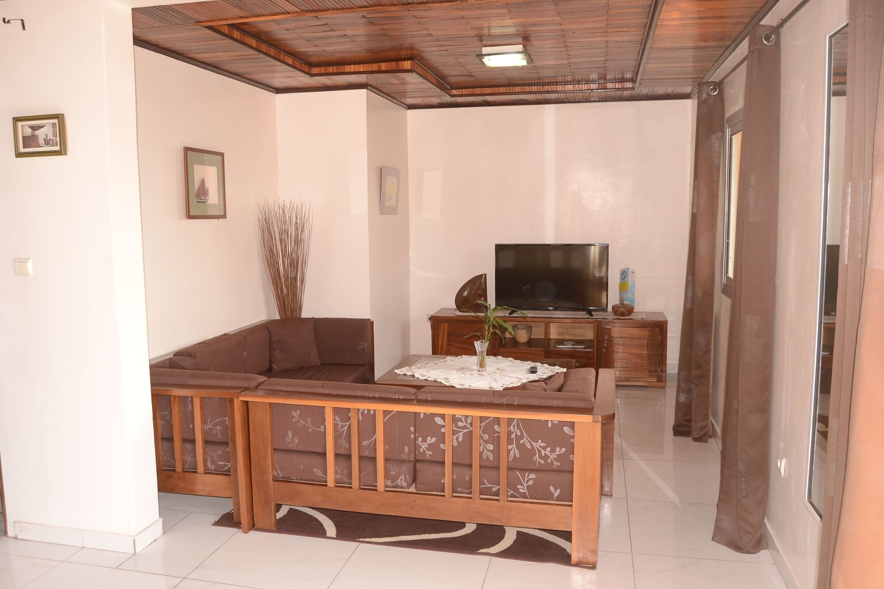 Una sala de estar con sofá, televisión y aparador de madera.