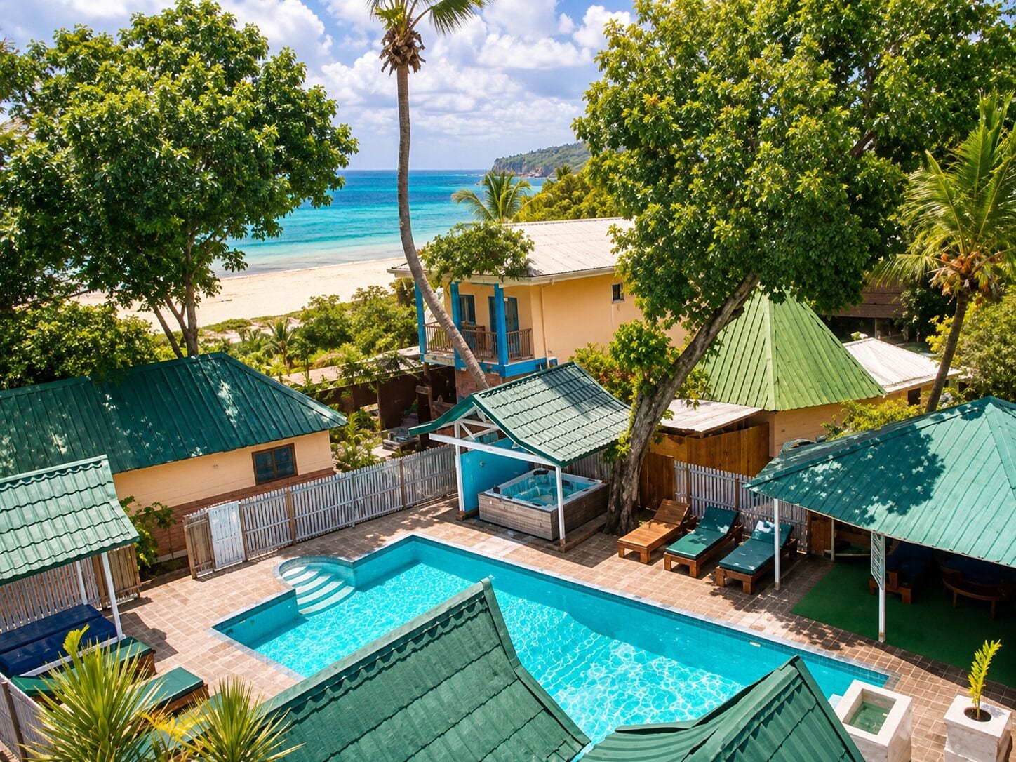 Un espace piscine avec vue sur la plage, entouré d’arbres et de bâtiments.
