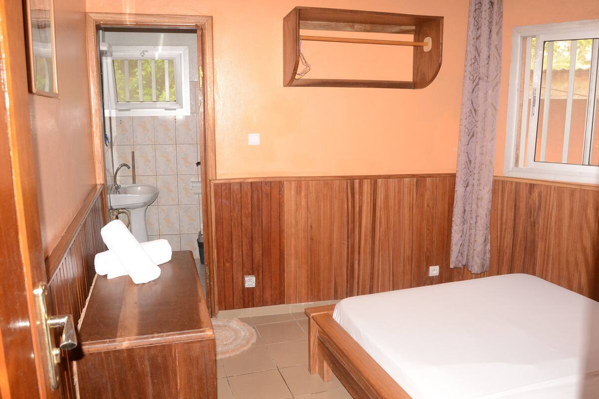 Une chambre à coucher avec un lit en bois, une commode en bois, un lavabo et une fenêtre.