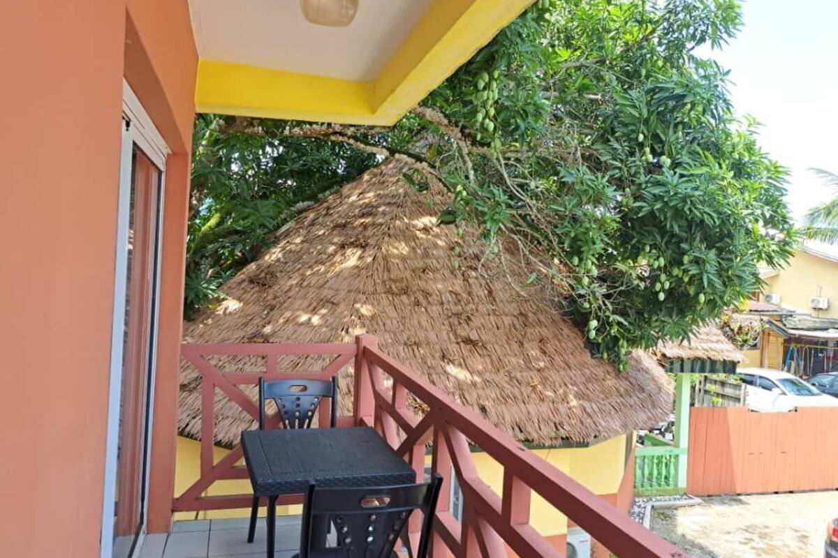 Un balcon doté d’un toit de chaume, d’une table et de chaises.