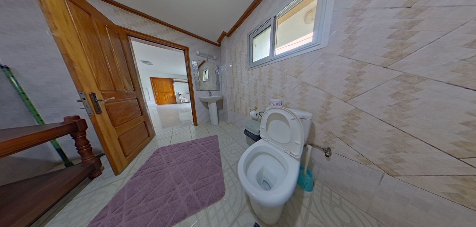 A bathroom with a toilet, a sink, a mirror, and a window.