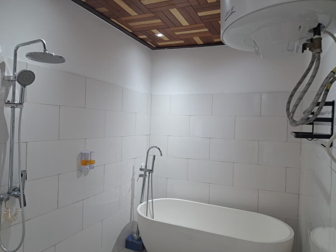 A modern bathroom with a freestanding bathtub, a showerhead, and a towel rack.