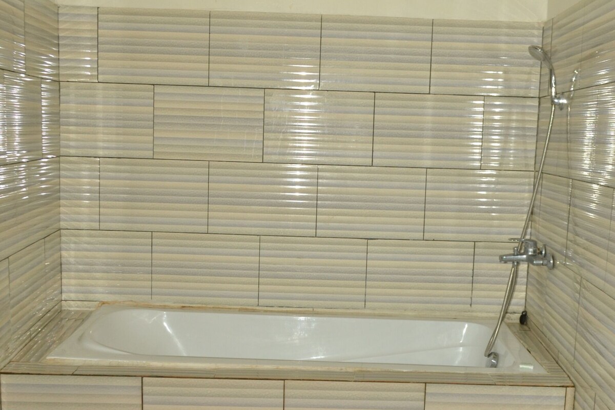 Une salle de bain avec une baignoire rectangulaire, des murs carrelés et un sol à motifs.