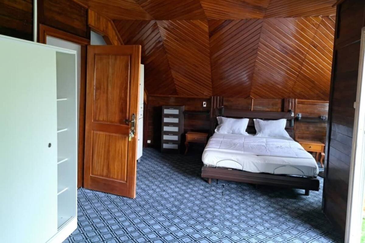 Une pièce aux murs lambrissés, contenant un lit, une armoire et une commode.