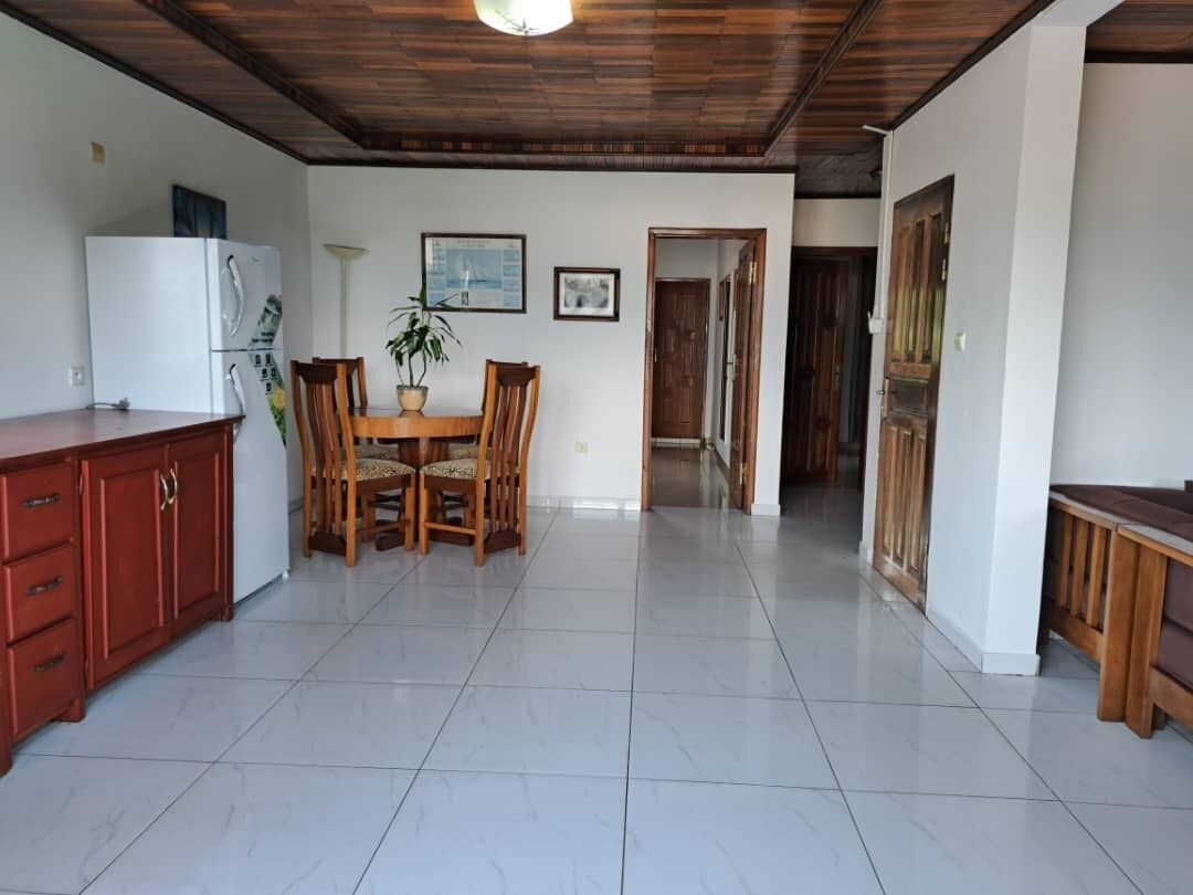 Una cocina amplia con comedor, armarios de madera y suelo de baldosas.