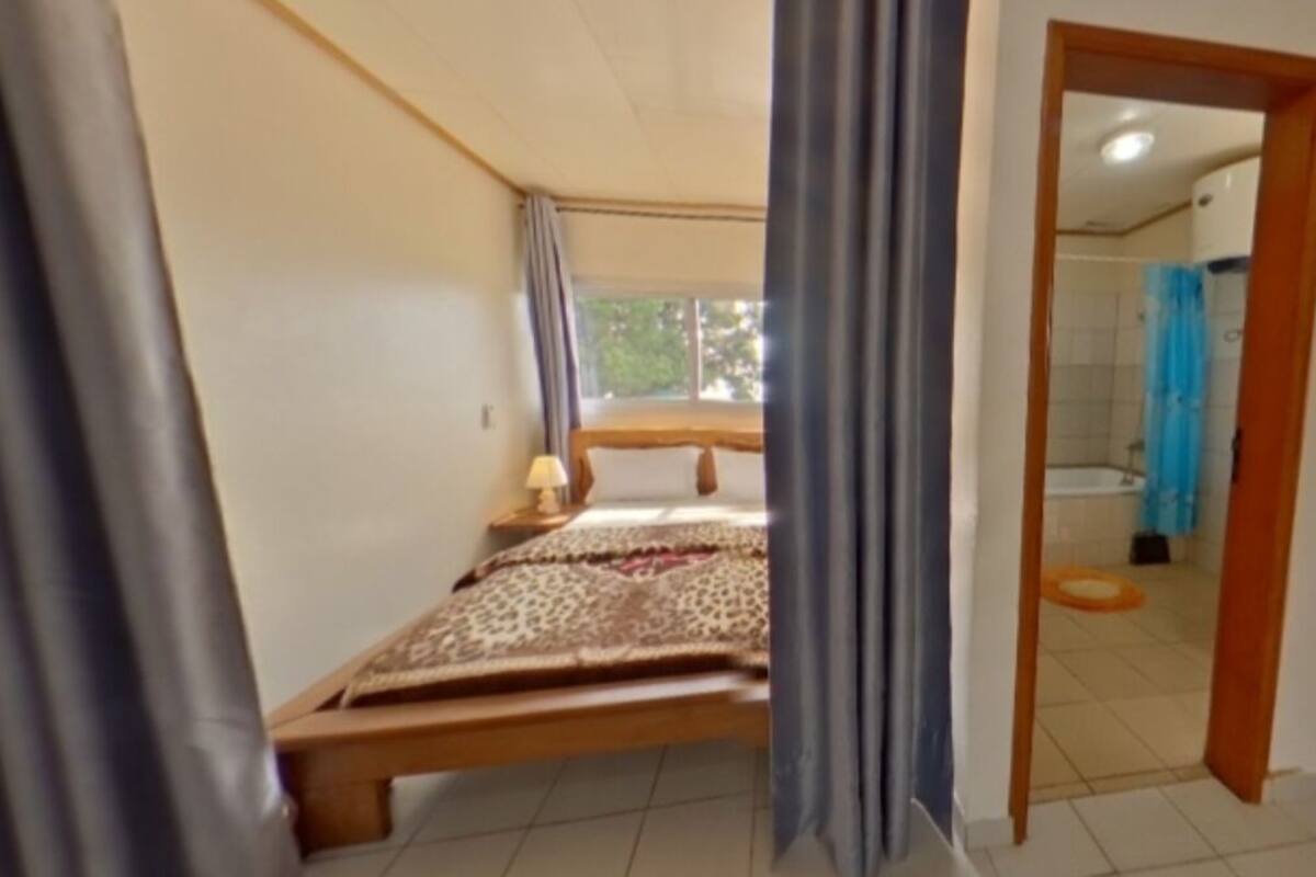 Une chambre à coucher avec un lit, une table de chevet, une fenêtre et une vue sur la salle de bain.