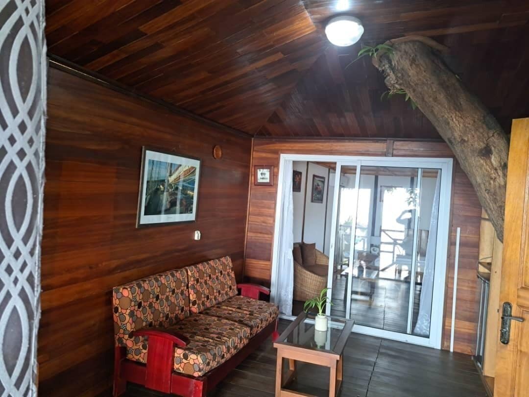 Un interior de madera con un sofá, una mesa de vidrio y una puerta que da a un balcón.