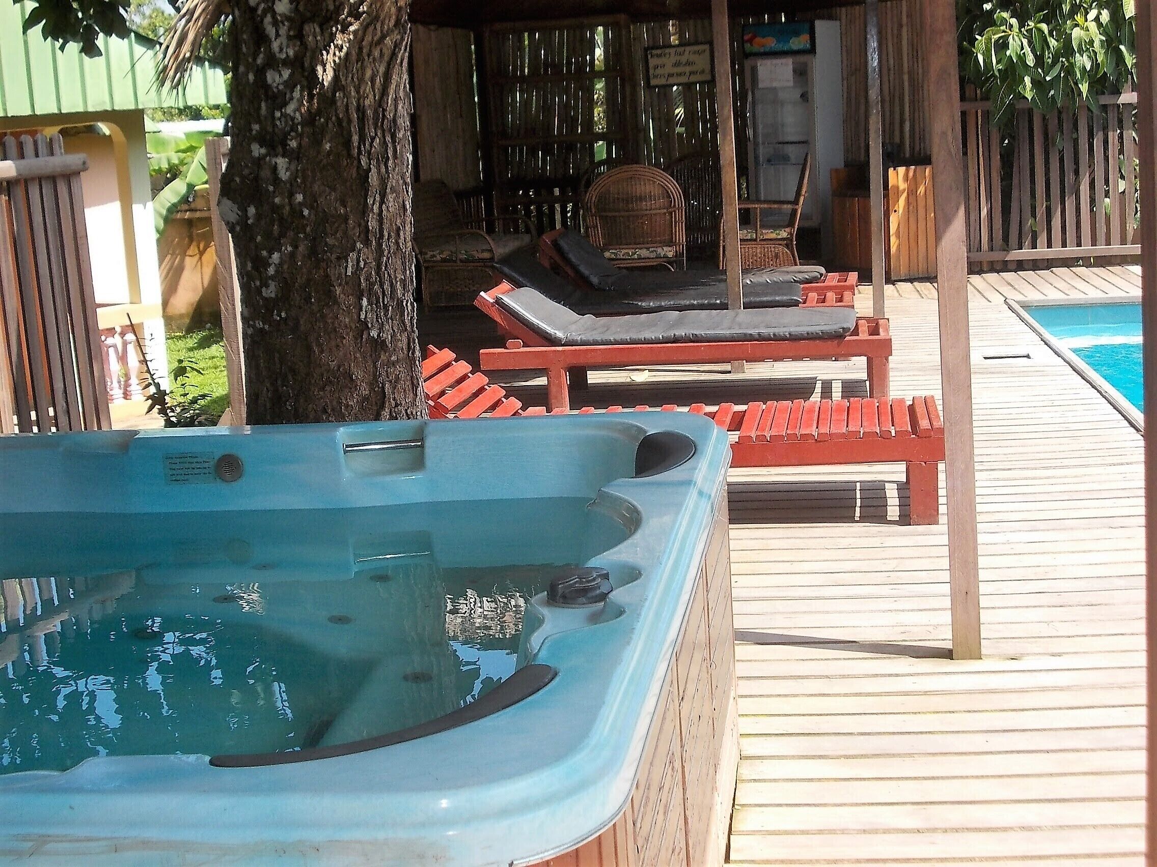 Ein Whirlpool mit Holzterrasse, Liegestühlen und Schwimmbecken.