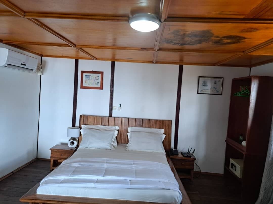 Une chambre à coucher avec un lit en bois, deux tables de chevet, une commode et une armoire intégrée.