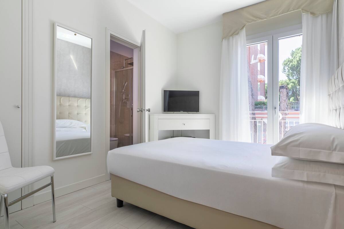 Une chambre à coucher avec un lit, un téléviseur posé sur une table de chevet, une chaise et une armoire.
