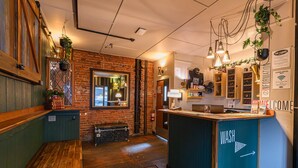 A cozy hotel lobby with a wooden bench, a reception desk, and a sign indicating the washroom location. - Cambie Downtown Hostel (Vancouver)