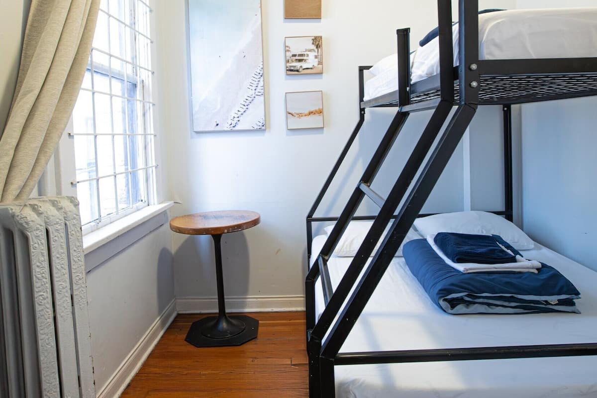 Une chambre avec un lit superposé, une petite table et un radiateur.