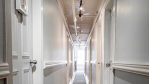 A hallway with a patterned carpet, white walls, and wooden flooring. - Cambie Downtown Hostel (Vancouver)