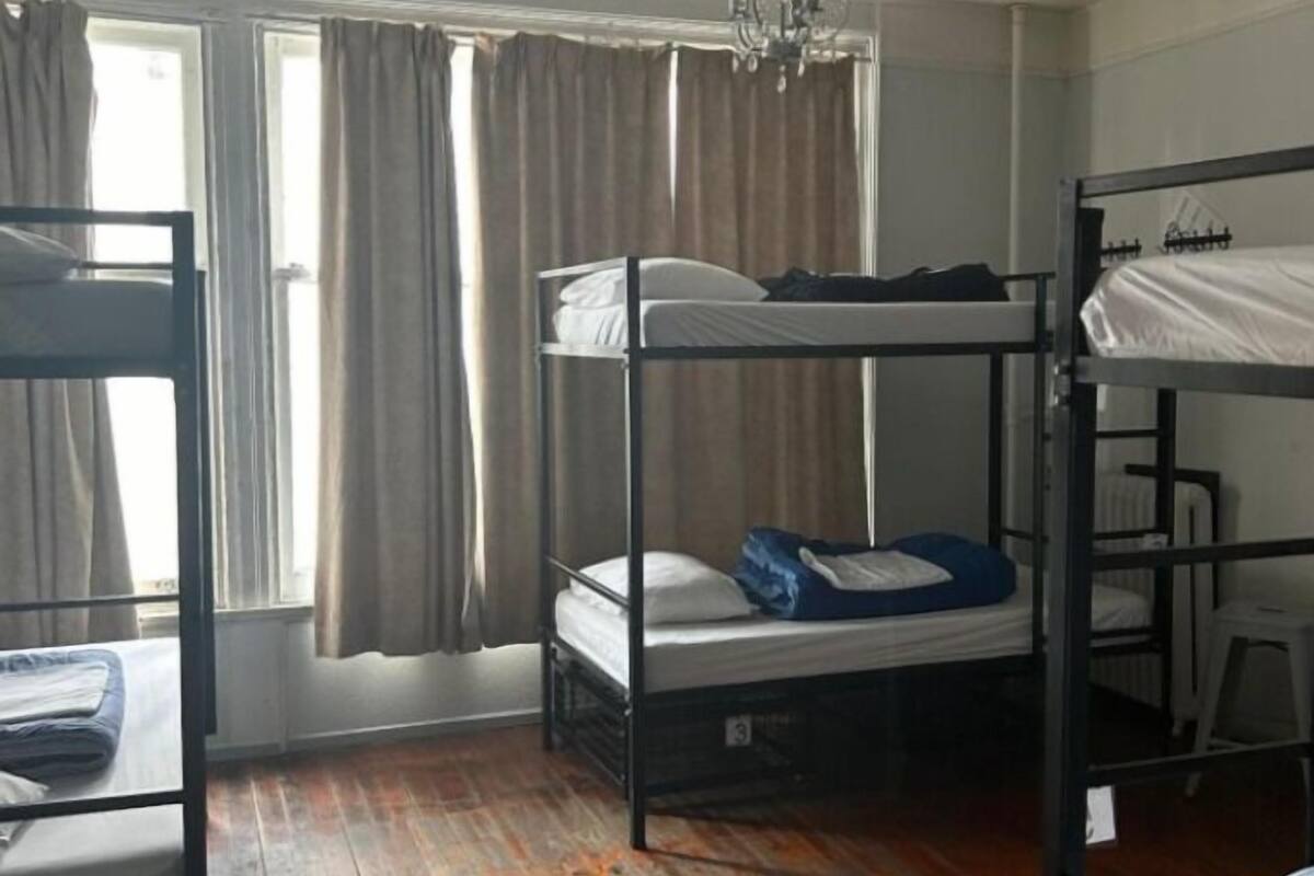 Un dormitorio con literas, una ventana con cortinas y un radiador.