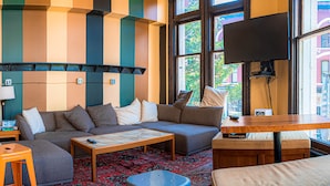 Una sala de estar acogedora con un sofá modular, una mesa de centro y un televisor montado en la pared.