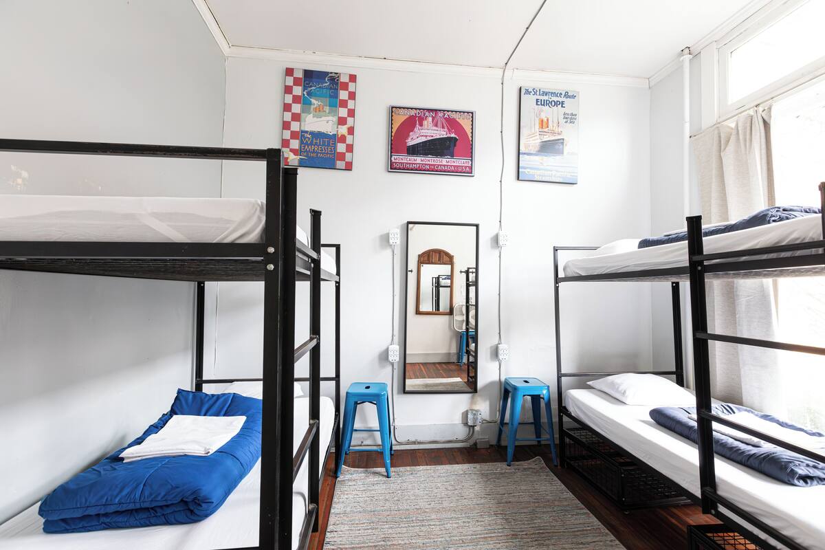 Un dormitorio con literas, un espejo y carteles en la pared.
