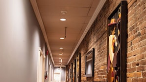Un pasillo con bancos de madera, pared de ladrillo con obras de arte e iluminación empotrada.