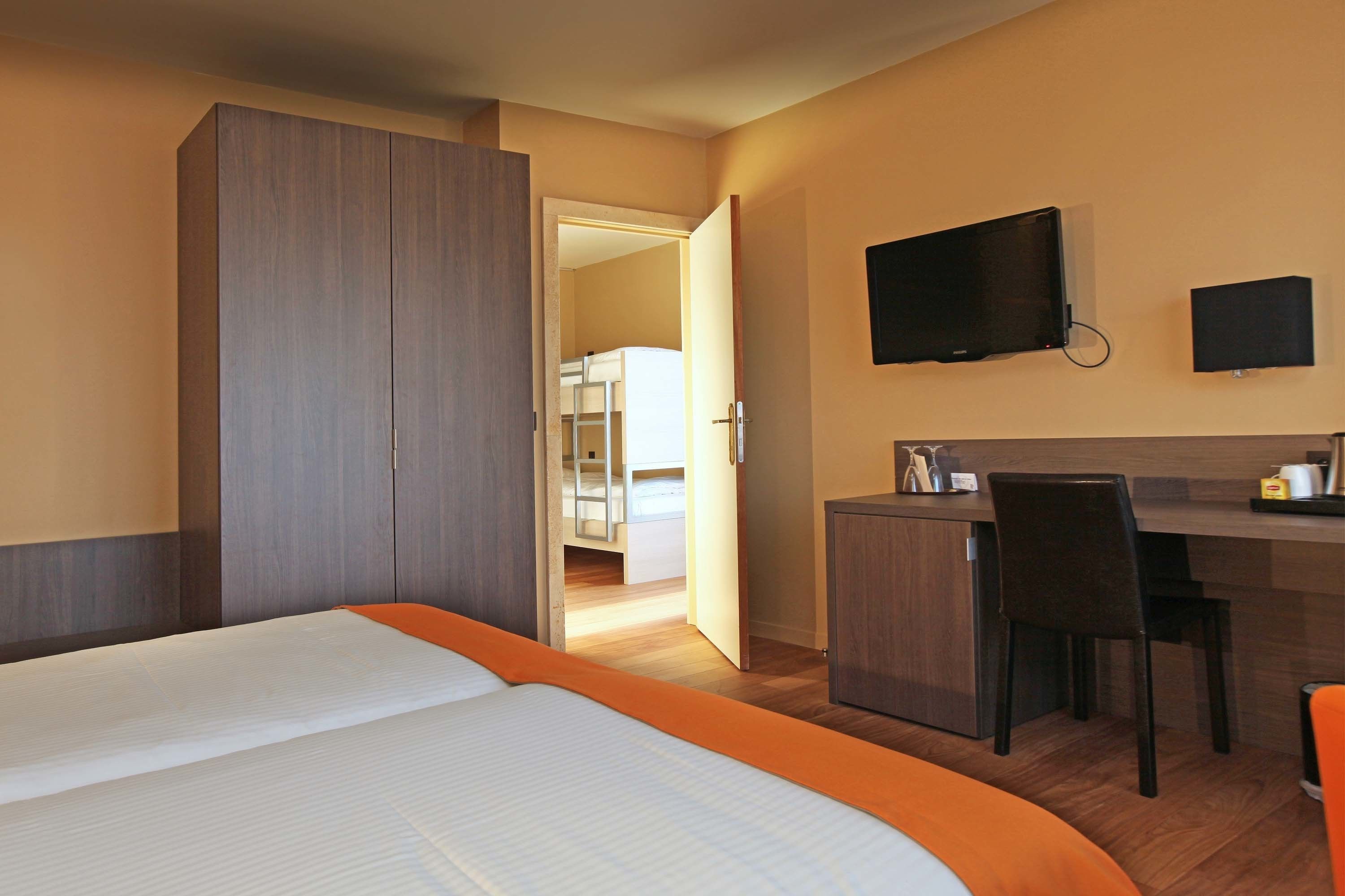 Une chambre d’hôtel comprenant un lit, un bureau, une chaise, une télévision et une armoire.