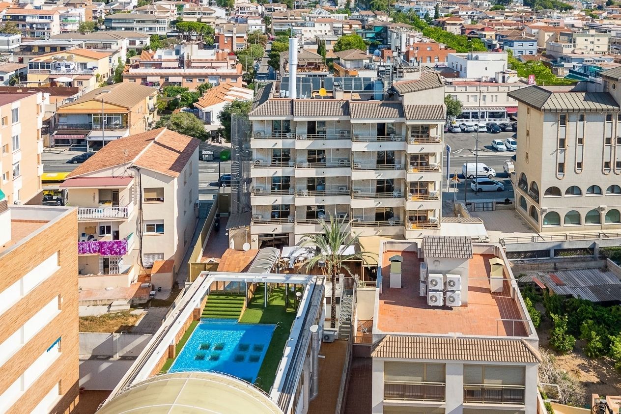 Un edificio de gran altura con varios balcones, una piscina en la azotea y vistas del entorno urbano.