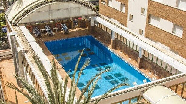 A rooftop swimming pool with lounge chairs and a covered seating area. - HOTEL VICTORIA (Calafell)