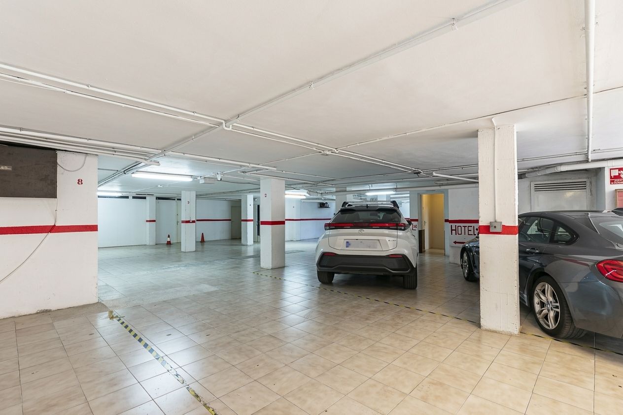 A parking garage with multiple levels, concrete pillars, and a few parked cars.