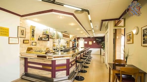 A bar area with a marble counter, stools, and framed pictures on the walls. - HOTEL VICTORIA (Calafell)