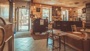 A cozy cafe interior with a wooden interior, a bar area, and a seating area with tables and chairs. - Downtown Forest Hostel & Camping (Vilnius)