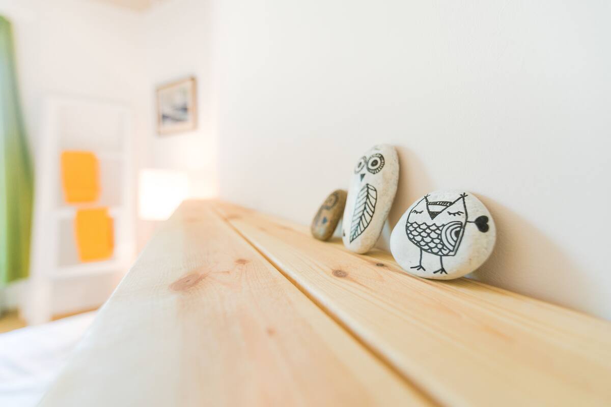 Un banco de madera con decoraciones de búhos pintados frente a una pared blanca.