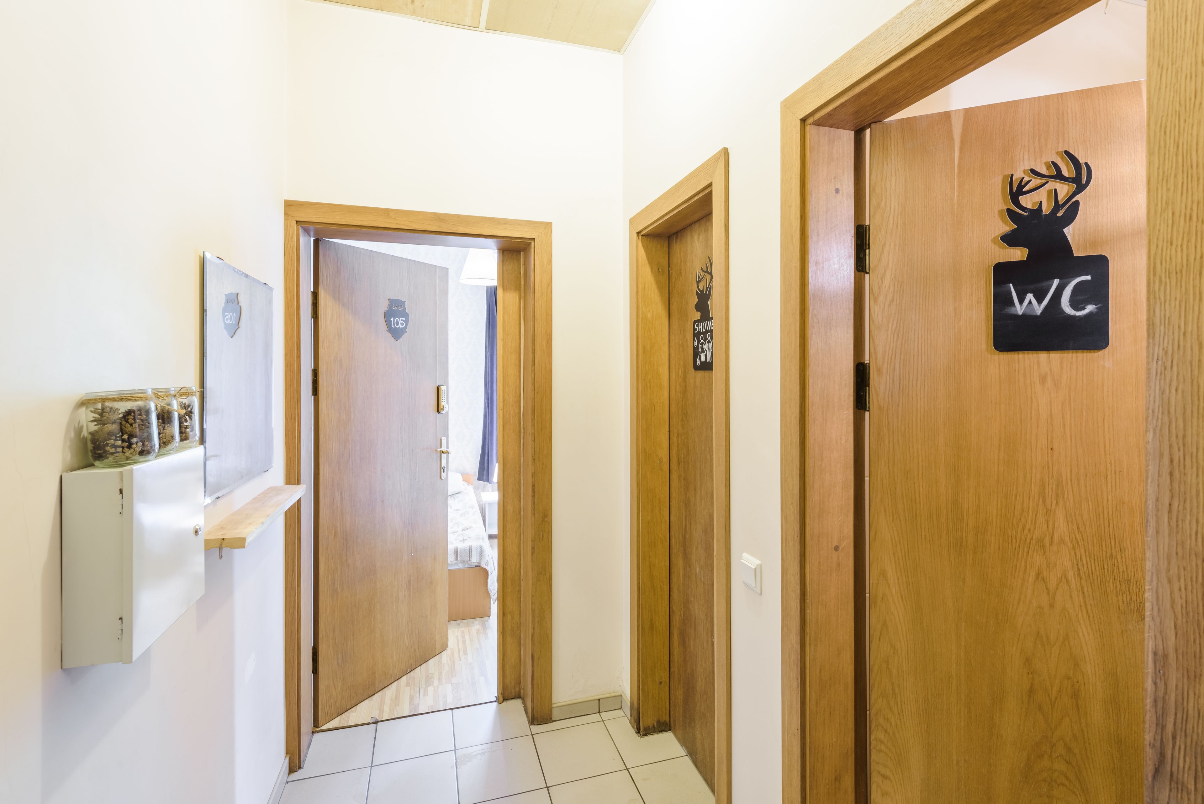 Un pasillo con puertas de madera, una con la figura de un ciervo y el letrero 'WC', y otra con el rótulo '1er piso'.