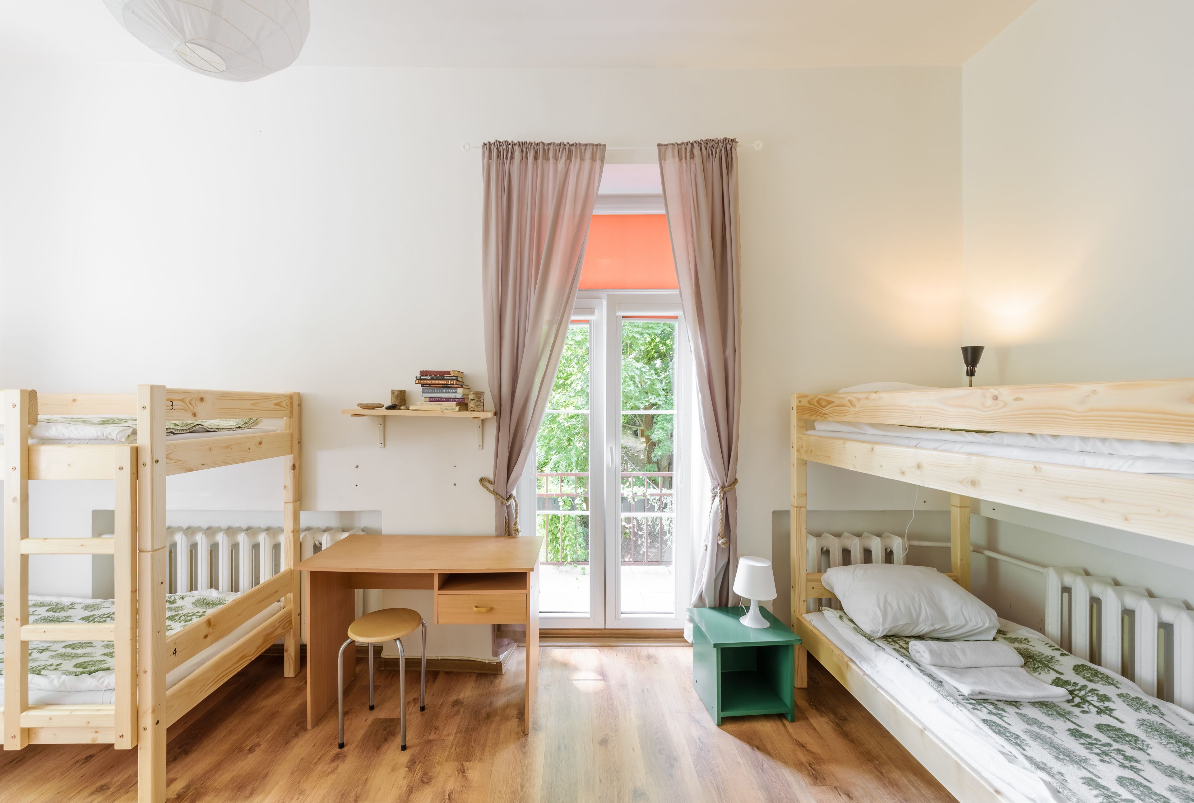 Una habitación con literas, un escritorio, una silla y una mesita de noche con lámpara.