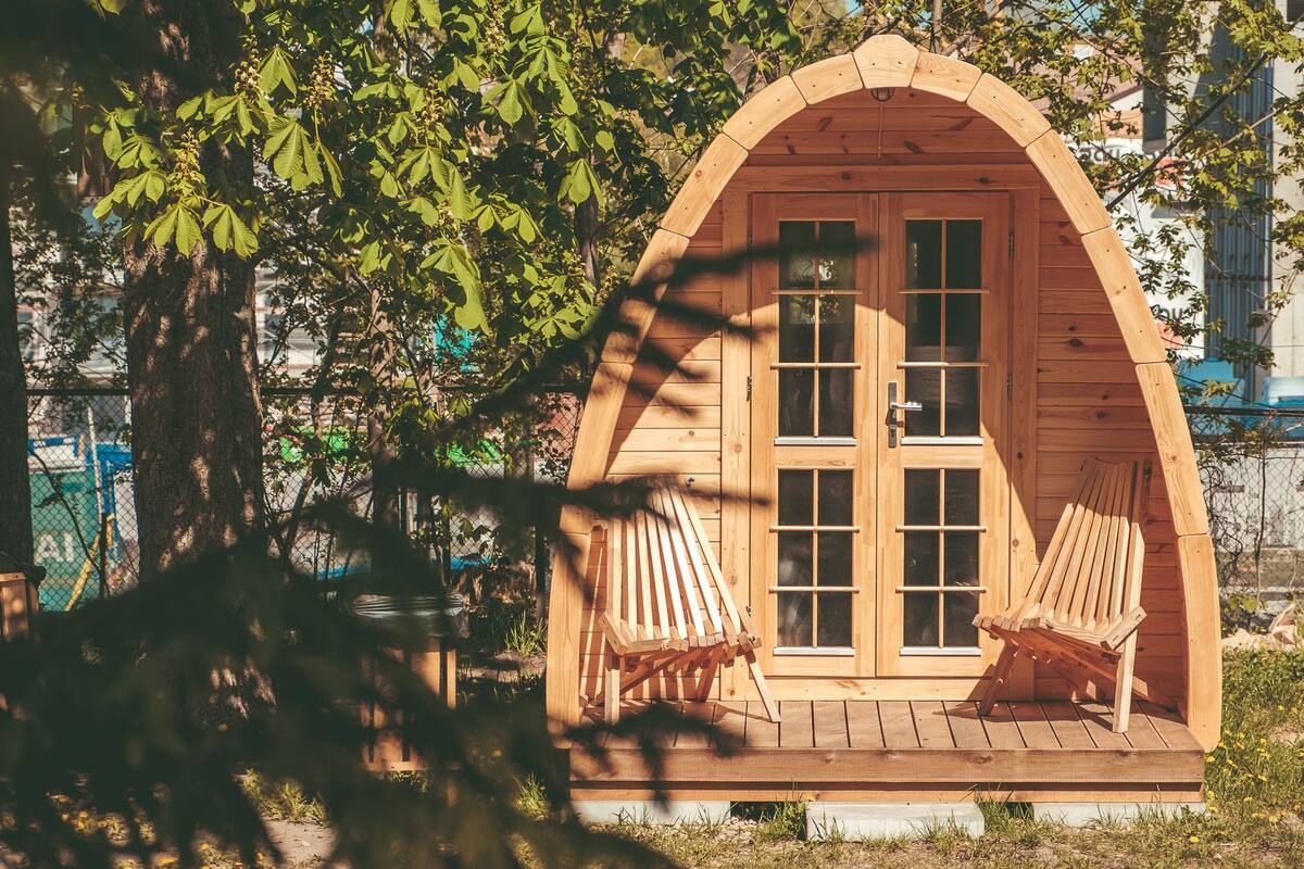Una cabaña de madera con dos sillas de madera y un ventanal grande.