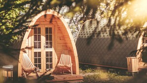 A wooden cabin with an arched entrance, two wooden chairs, and a small table. - Downtown Forest Hostel & Camping (Vilnius)