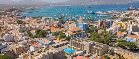 Un pueblo costero con un puerto deportivo, edificios coloridos y montañas al fondo.