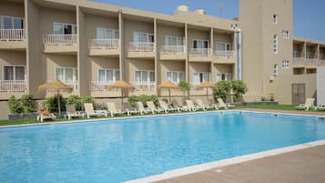 Un hotel con piscina, varios balcones y sillones de descanso.