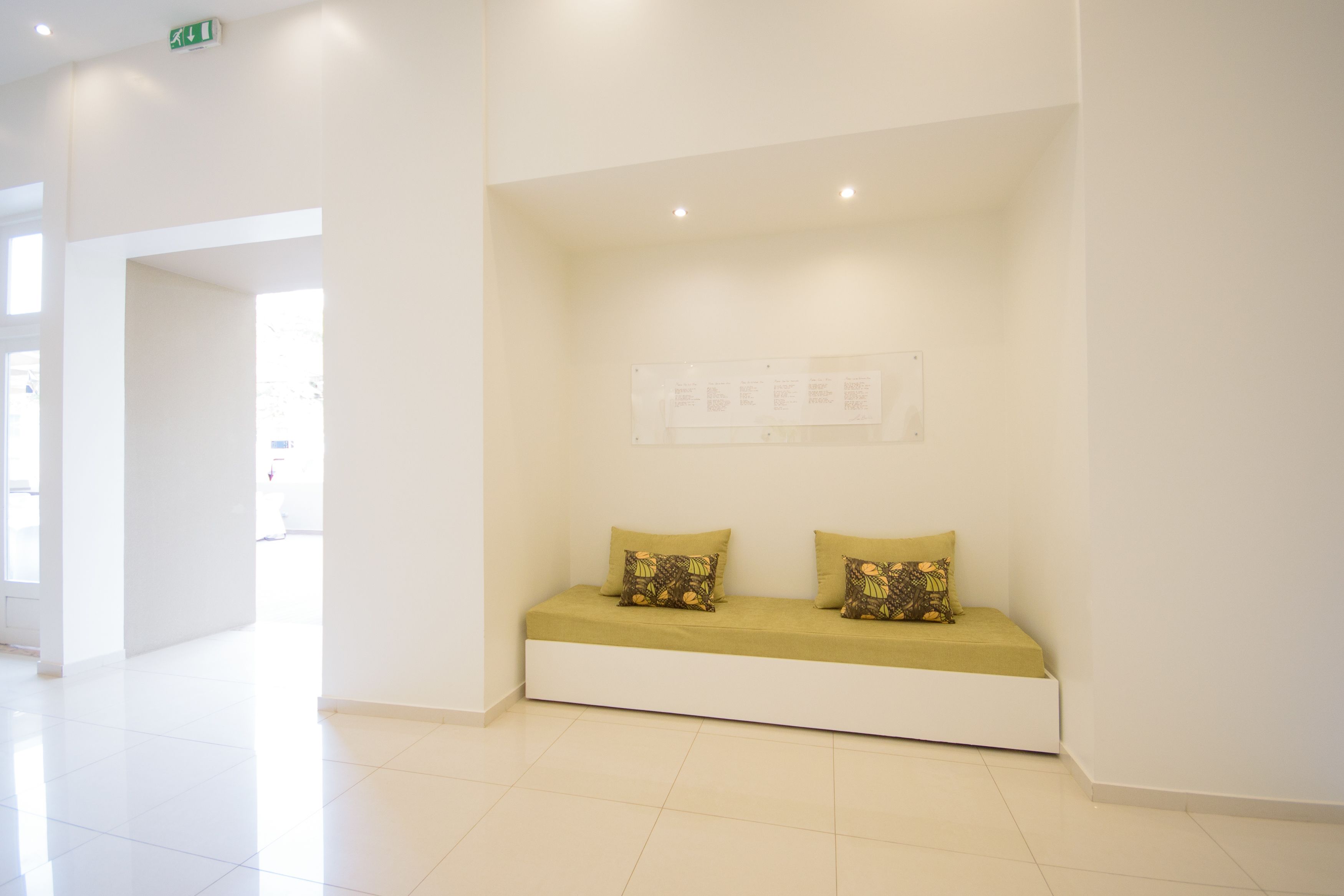 A clean, modern waiting area with a bench and a wall-mounted sign.
