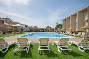 Una piscina con sillas de descanso y un edificio al fondo.