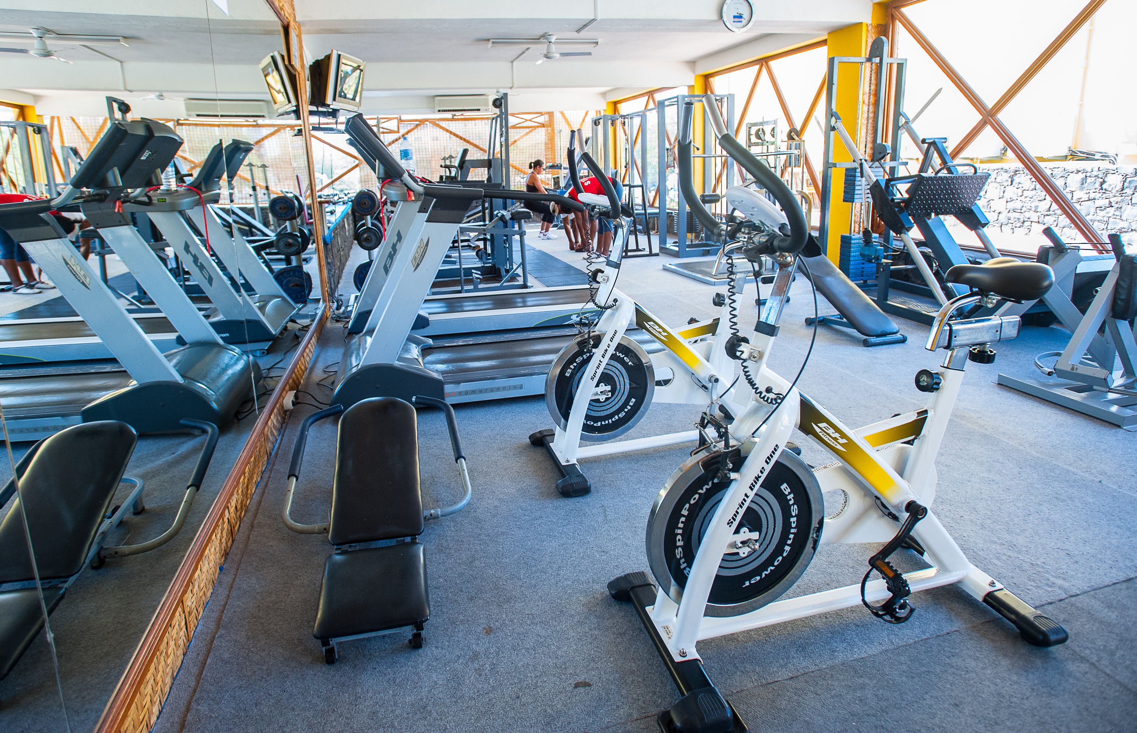Une salle de sport équipée de divers appareils d’exercice, notamment des tapis de course, des vélos d’appartement et des appareils de musculation.