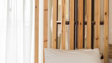 A bed with a beige patterned bedspread, a white pillow, and a wooden headboard with vertical slats.