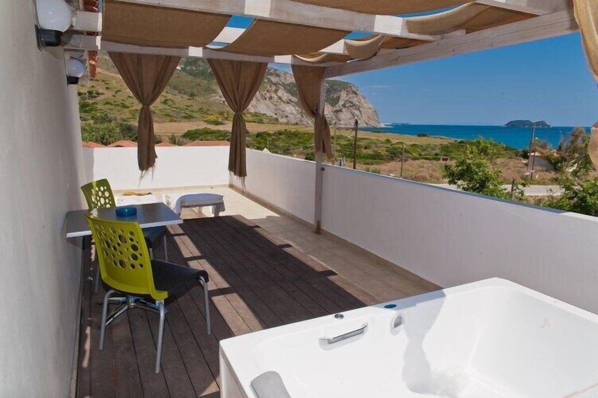 A balcony with a wooden floor, a white bathtub, and a table with chairs.