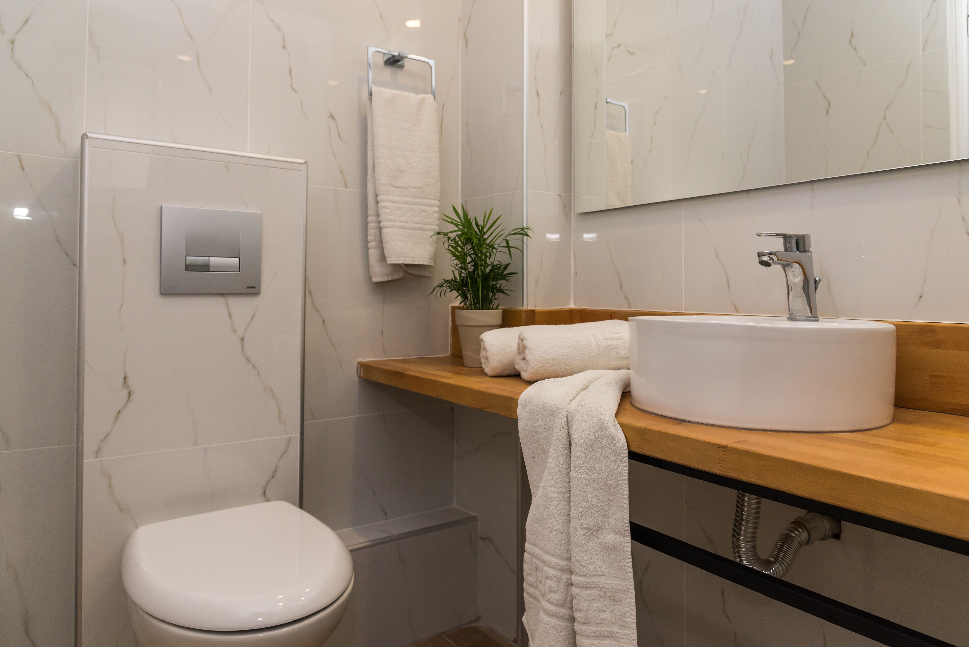 Et moderne badeværelse med toilet, vask med spejl og et håndklædestativ.