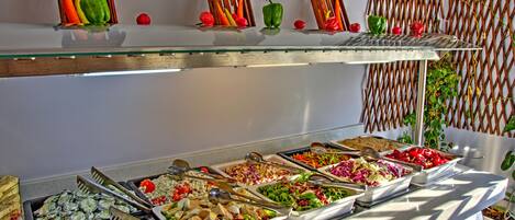 A buffet with various food options and decorative elements like wooden houses and a woven wall.