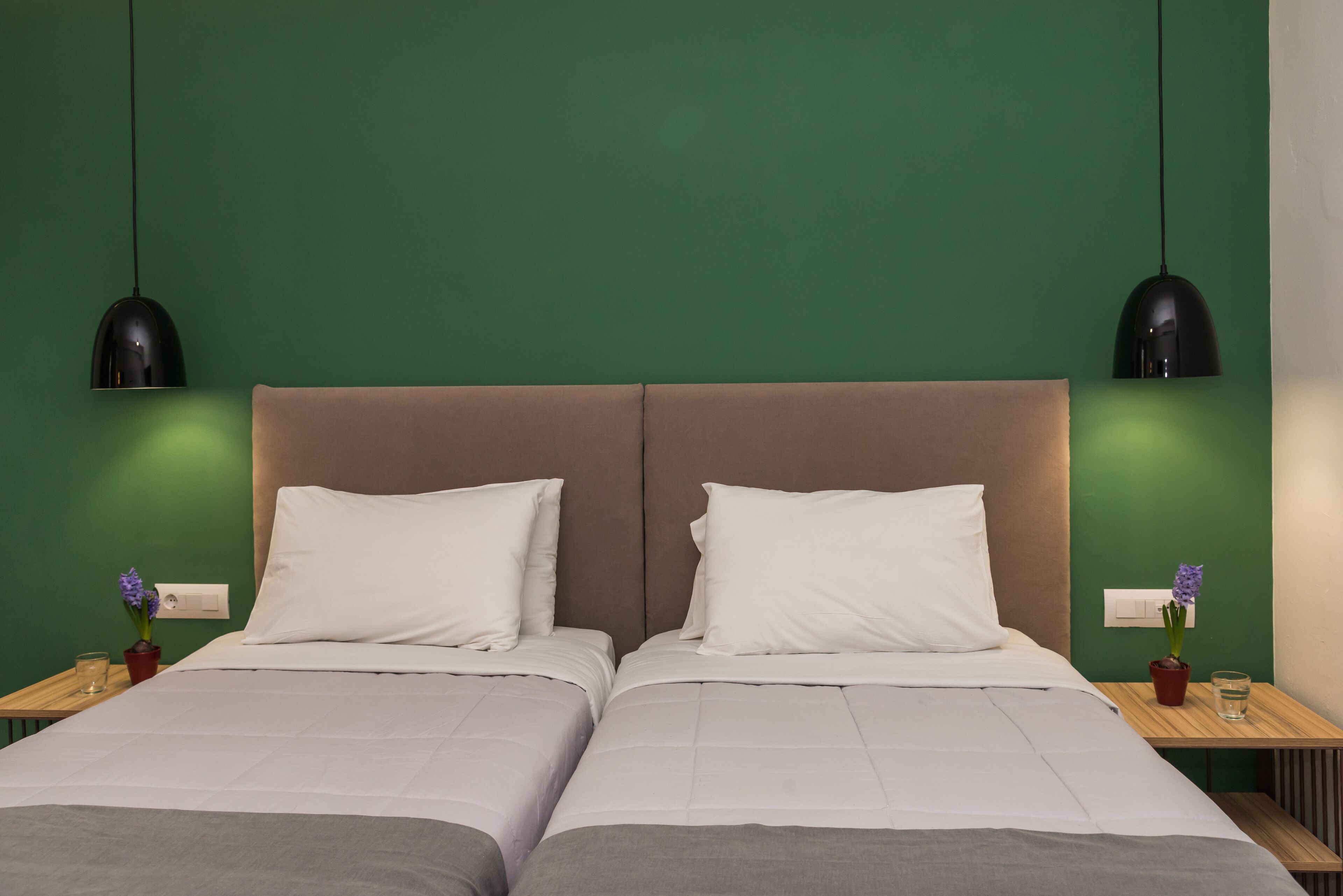 Uma cama de casal com cabeceira, duas mesas de cabeceira e uma parede verde.