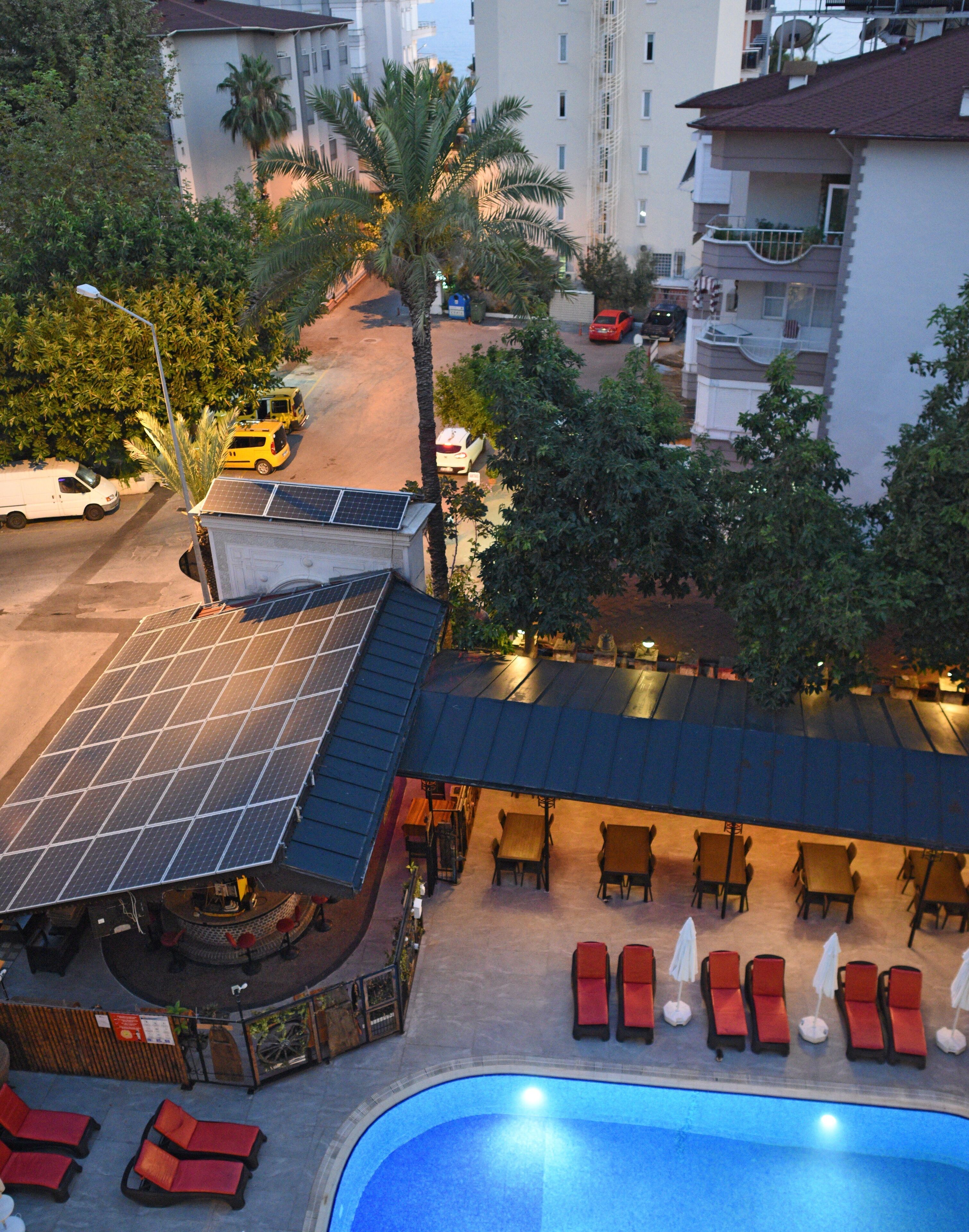 A rooftop bar with a poolside area, solar panels, and a view of the surrounding buildings and street.
