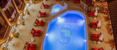 A rooftop pool area with red lounge chairs and a sign reading "FATH OTEL".