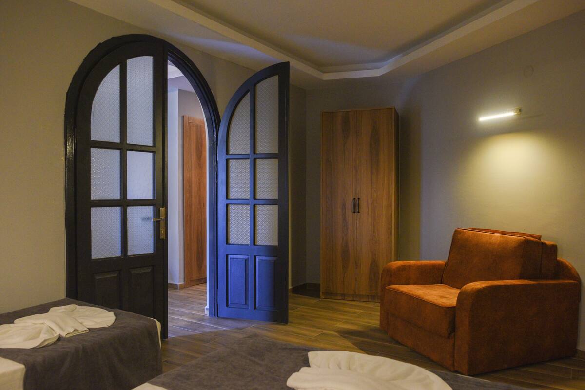 A room with a bed, a blue door, a wooden wardrobe, and an orange chair.