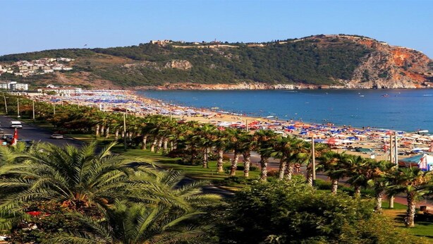 A beach with palm trees, umbrellas, and a clear view of the sea. - Fatih Hotel Kleopatra (Alanya)