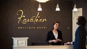 Bancada de recepção no Kavaher Boutique Hotel, com uma placa, um dispositivo Philips e um candelabro.